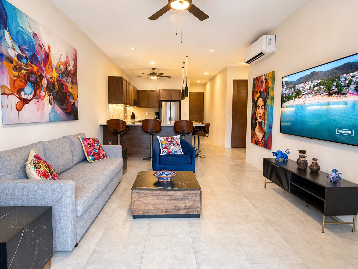 Casa Racél's full living area — sofa, kitchen bar, and original Mexican art on every wall