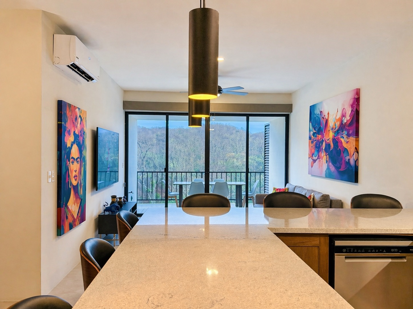Kitchen island looking out to the balcony — Frida and splash-art canvases frame the view