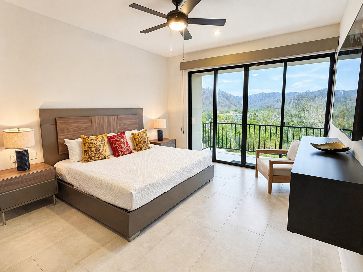 Primary suite — king bed, balcony with mountain views, and a reading chair