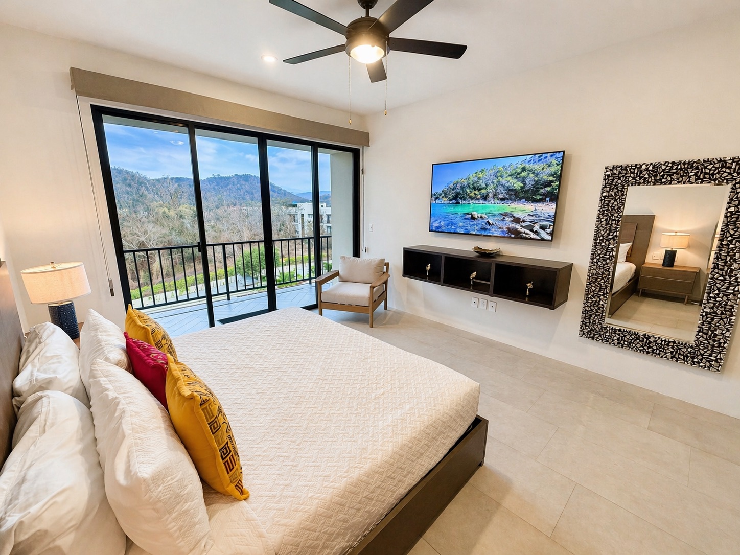 Smart TV, mosaic-frame mirror, and balcony access from the primary suite