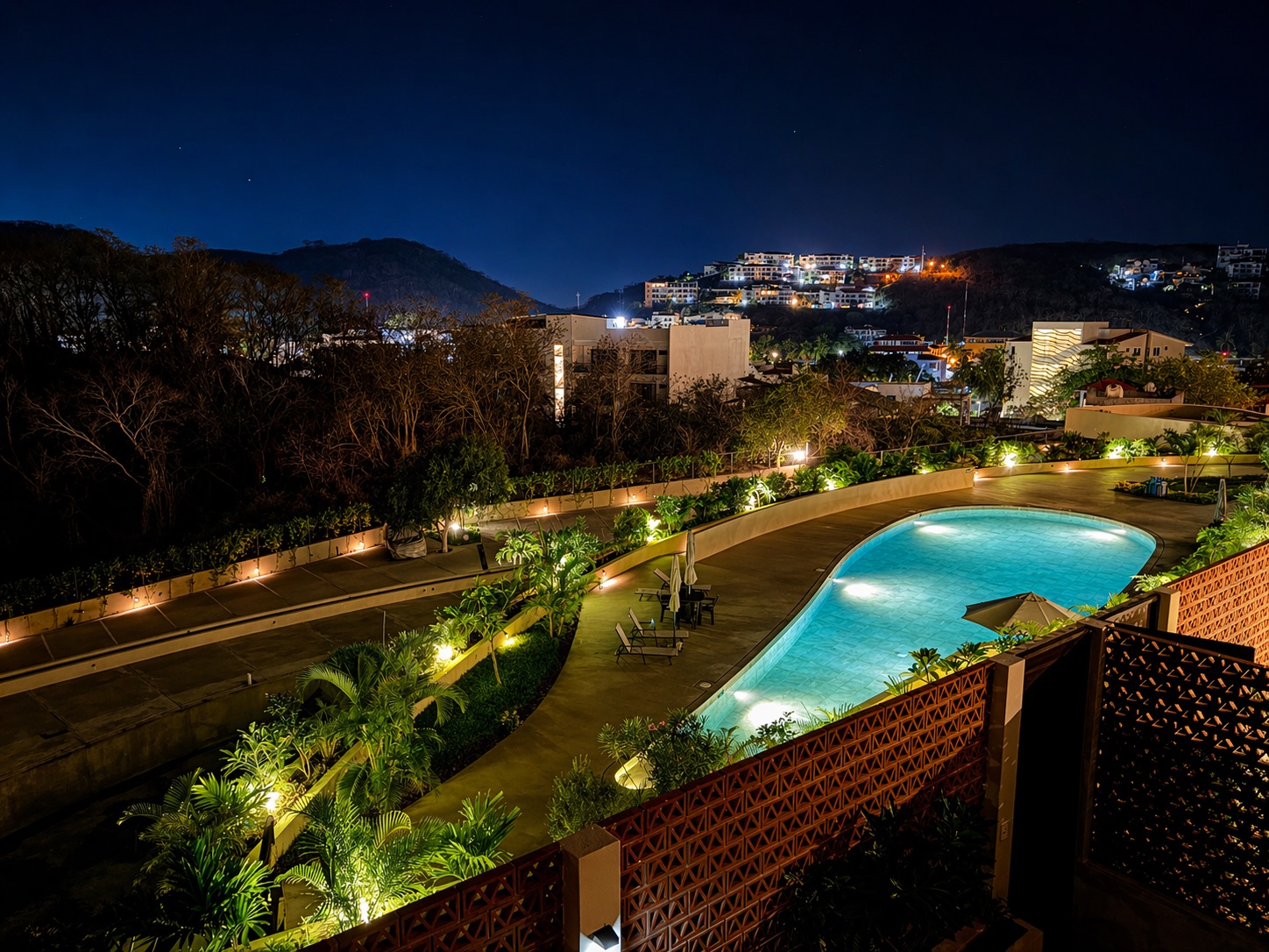 Nirú pool at blue hour — accent lighting and city lights on the hillside