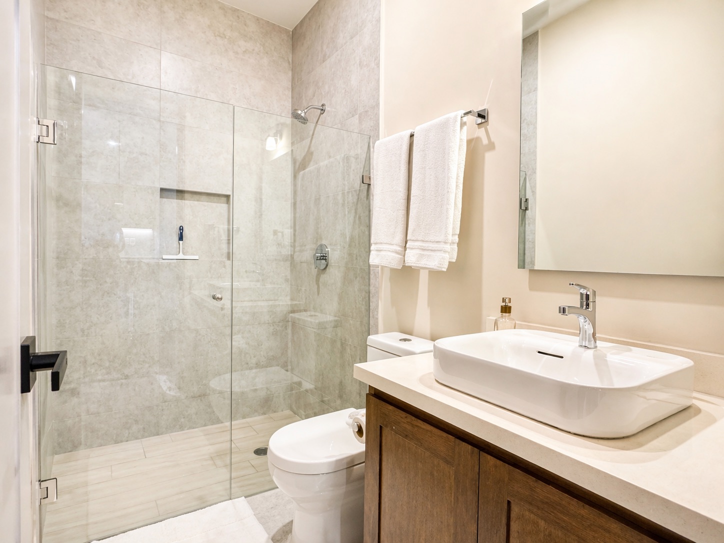 Spa-style bathroom — frameless glass walk-in shower and vessel sink on wood vanity